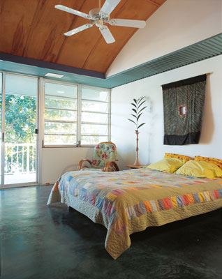 
Breezes are facilitated through Beth and Ron's bedroom with a beachside wall of windows and sliders, high ceilings, and fans. Thin birch panels line the ceiling, giving the room a warm glow.
